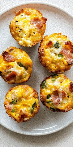 four mini muffins on a white plate with cheese and spinach toppings