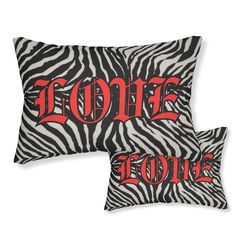 two zebra print pillows with the words home and love in red letters on black background