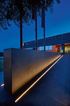 a building that has some lights on the side of it and trees in front of it