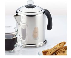 a tea pot and some cookies on a white table next to a cup of coffee