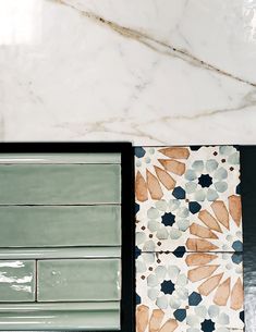 two green and white tiles sitting next to each other on top of a marble counter