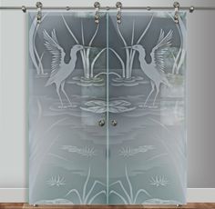 a glass sliding door with two birds in the water and lily pads on the ground