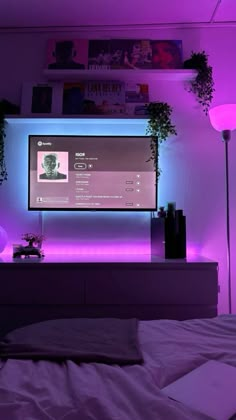 a flat screen tv mounted to the side of a wall next to a purple light