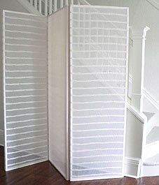 a white room divider sitting on top of a hard wood floor next to a stair case