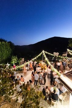 a group of people standing around each other on top of a patio next to trees