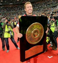 a man is holding up a trophy in front of a large group of people at a sporting event