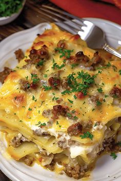 a white plate topped with lasagna covered in meat and cheese next to a fork