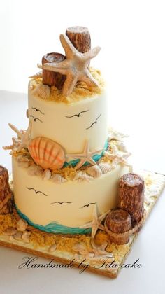 a three tiered cake with seashells and starfish on top