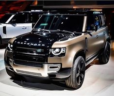 two suvs are on display at an auto show, one is gold and the other is black