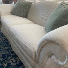 a white couch with pillows on it in front of a blue and white carpeted floor