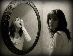 a woman looking at herself in the mirror with her hand on her face and mouth open