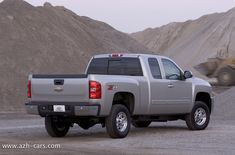 a silver truck parked in front of a pile of dirt