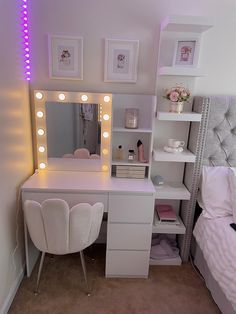 a white vanity with lights on it and a bed in the corner next to it