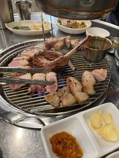 the grill is full of meats and sauces on it's sides, including potatoes