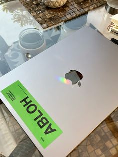 an apple laptop sitting on top of a glass table with the word holb written on it