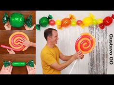 a man holding a giant candy lollipop in front of a wall with balloons and streamers