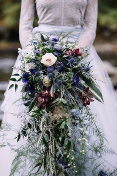 a bride holding a bouquet of flowers and greenery