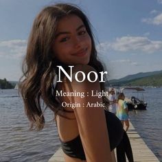 a beautiful young woman standing on top of a pier next to the ocean with text reading noor meaning & light origin arabic