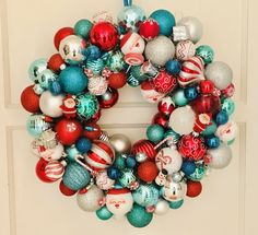 a christmas ornament wreath hanging on the front door with ornaments all over it