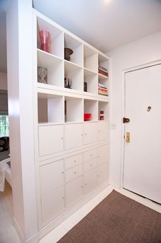 an empty room with white bookcases on the wall and carpeted flooring