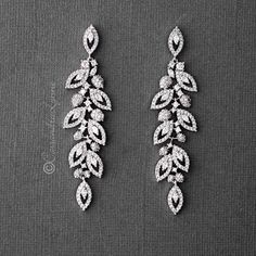 two pairs of diamond earrings with leaves on them, one in white gold and the other in silver