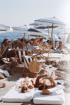 people are lounging on the beach under umbrellas