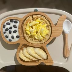 a wooden plate topped with waffles and blueberries next to yogurt