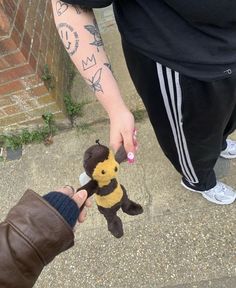 a person holding a small stuffed animal in their hand while another person holds it up