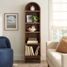 a living room filled with furniture and a book shelf in front of a window next to a blue chair