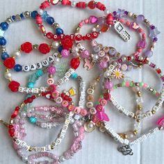 a bunch of bracelets that are sitting on a white tablecloth with words written in them