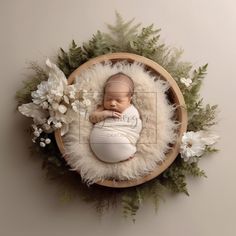 a newborn baby is sleeping in a basket surrounded by white flowers and greenery on the wall