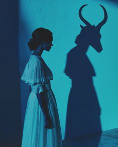 a woman standing in front of a shadow of a goat