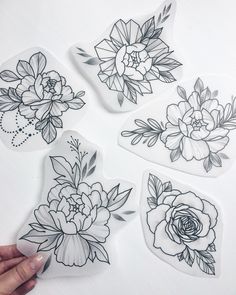 four stickers with flowers on them and one being drawn by someone's hand