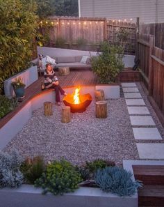 a woman sitting on a bench next to a fire pit in the middle of a yard