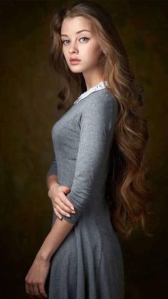 a woman with long hair is posing for a photo in a gray dress and white collared shirt