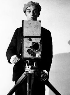 a man standing in front of a camera with his hands on the tripod and looking at the camera