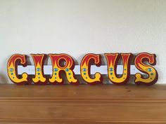 a wooden sign that says circus sitting on top of a mantle next to a wall