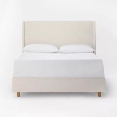 a bed with white sheets and pillows on it's headboard, against a white background