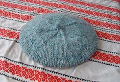 a blue knitted beanie sitting on top of a red and white table cloth