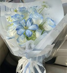 a bouquet of blue and white flowers sitting in the back seat of a car,