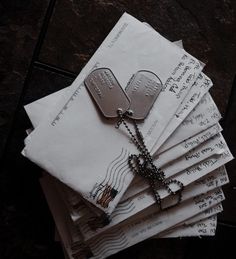 a stack of envelopes with dog tags and chains on them sitting next to each other