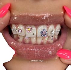 a woman's mouth with pink and white nail polish on her teeth, decorated with jewels