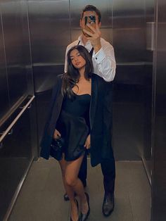 a man taking a selfie with a woman in front of him on an elevator