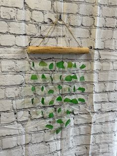 a white brick wall with green leaves hanging from it's sides and a wooden frame