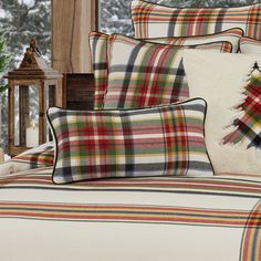 a bed with plaid sheets and pillows in front of a christmas tree on the wall