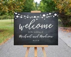 a welcome sign on an easel in front of some trees