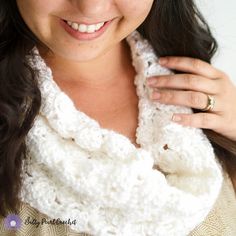 a woman wearing a white crocheted cowl with a ring on her finger