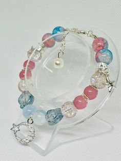 This beautiful bracelet features a harmonious blend of pink, blue, and clear beads, each one uniquely textured and polished to catch the light. The centerpiece is a delicate silver moon and star charm, adding a touch of celestial elegance. The bracelet is adorned with small, intricate charms, including a silver starfish and a pearl dangle, enhancing its whimsical and enchanting appeal. Perfect for adding a splash of color and a hint of magic to any outfit, this bracelet is both playful and sophi Silver Bracelet With Moon Charm And Round Beads, Silver Bracelets With Moon Charm And Round Beads, Clear Beads, Moon And Star, Silver Moon, Lovely Jewellery, Star Charms, Beautiful Bracelet, Starfish