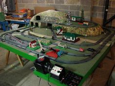 a model train set is on display in a room with green tables and chairs around it