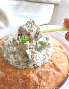 a spoonful of dip being held over a baked bread